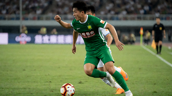 足球比赛现场画面，球员在草坪上争抢球权，看台上观众正在观赛